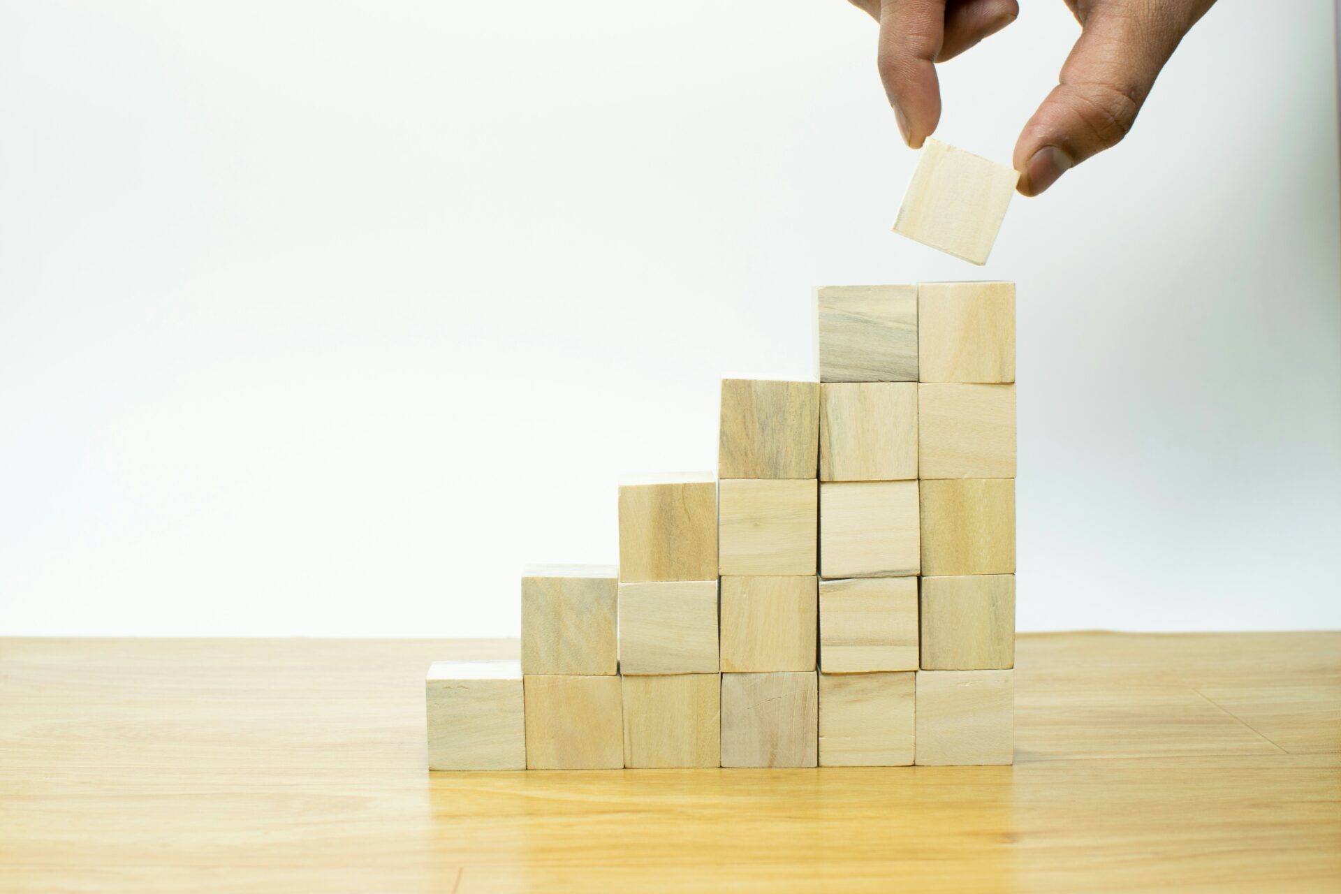 Hand stacking wooden blocks used as an image in a blog about spotting market opportunities.